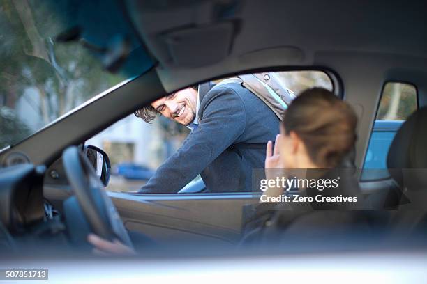 young businesswoman driving and waving at male cyclist - car interior side stock pictures, royalty-free photos & images
