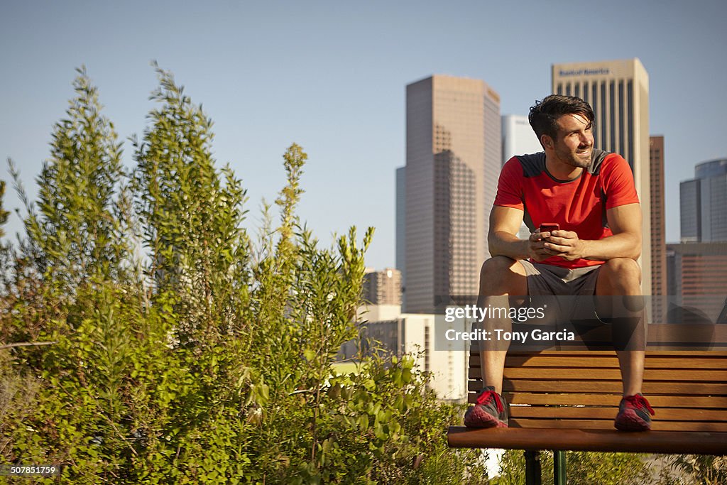 Young male runner taking a break on park bench