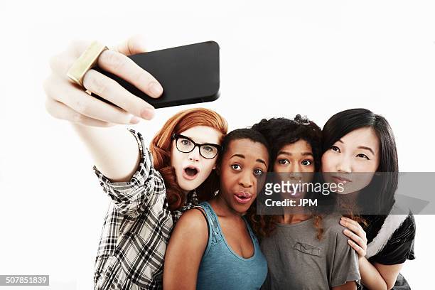 studio portrait of four young women taking selfie on smartphone - taking selfie white background stock pictures, royalty-free photos & images