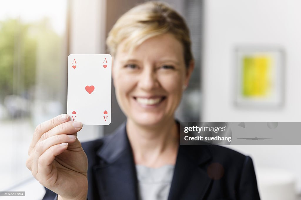 Portrait of mature businesswoman holding up ace playing card