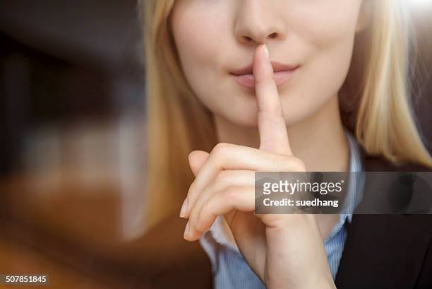 close up cropped image of young businesswoman with finger on lips - finger on lips stock pictures, royalty-free photos & images