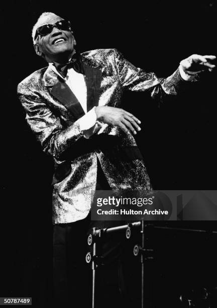 American singer, pianist and songwriter Ray Charles stands and gestures while performing in concert, 1980s.