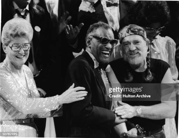 American musicians Minnie Pearl, Ray Charles and Willie Nelson smile together at an unidentified event, 1980s.