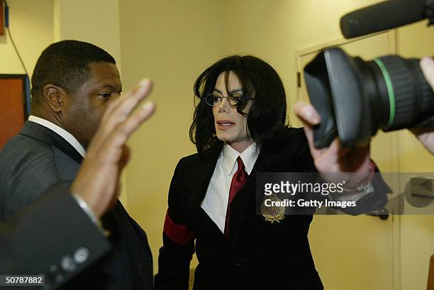 Pop star Michael Jackson and his bodyguard cover the lens of a camera to avoid being filmed as he enters the Santa Maria Courthouse April 30, 2004 in...