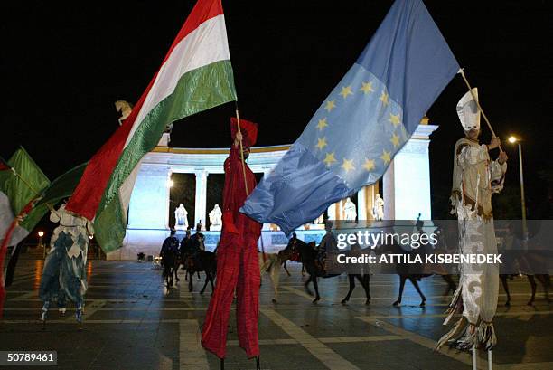 Hungarian men on stilts dancing with EU and Hungarian flags at the monument of the statues of Hungarian kings at the Heros square of Budapest on...