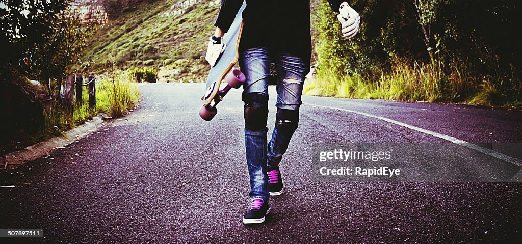 The legs of a longboarder trudging back up the hill