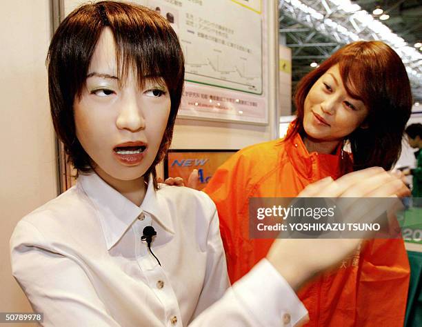 Humanoid robot "Actroid", at 1.58-m in height and 30-kg in weight, developed by Japanese robotic venture Kokoro, brushes away a hand as a woman...