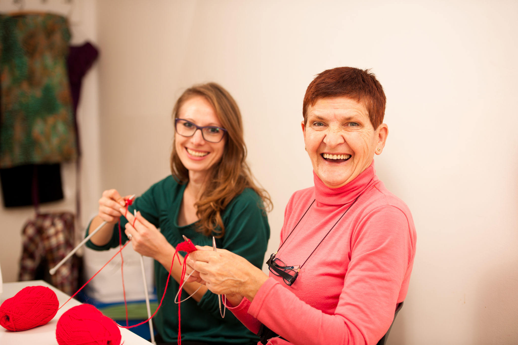 Women knitting with red wool. Eldery woman transfering knitting knowledge Women knitting with red wool. Eldery woman transfering knitting knowledge