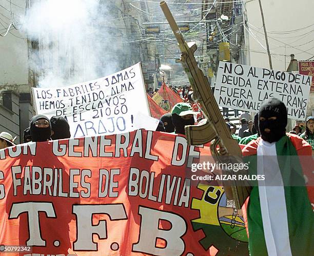 Protester, part of a group of activists similary clad and wearing balaclavas, waves his mock AKM rifle during a MayDay march in downtown La Paz,...