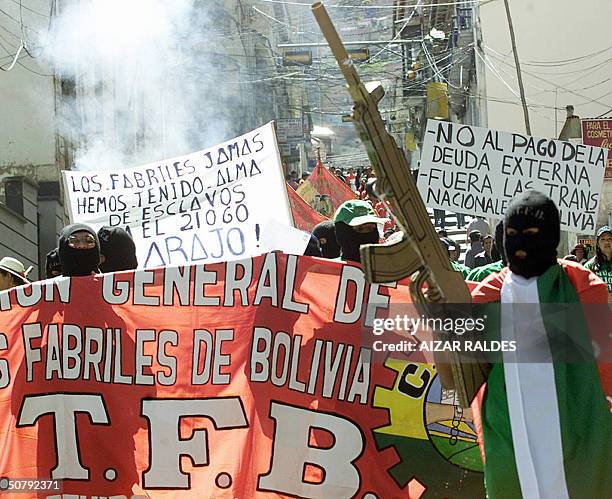 Protester, part of a group of activists similary clad and wearing balaclavas, waves his mock AKM rifle during a MayDay march in downtown La Paz,...