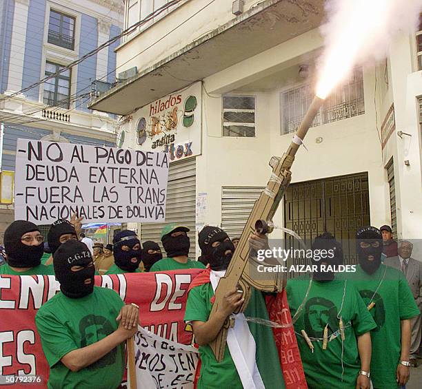 Protester, part of a group of activists similary clad and wearing balaclavas, fires a rocket through his mock AKM rifle, while two others carry...