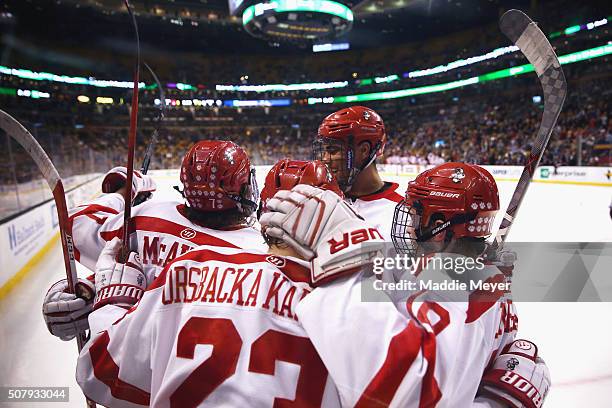 Jakob Forsbacka Karlsson of the Boston University Terriers and Jordan Greenway celebrate with Charlie McAvoy of the Boston University Terriers after...