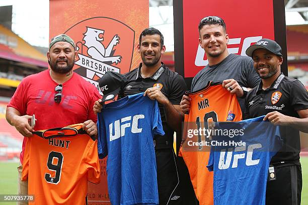 Fighters Mark Hunt and Frank Mir exchange shirts with Brisbane Roar players Henrique and Jamie Young during a media opportunity at Suncorp Stadium on...