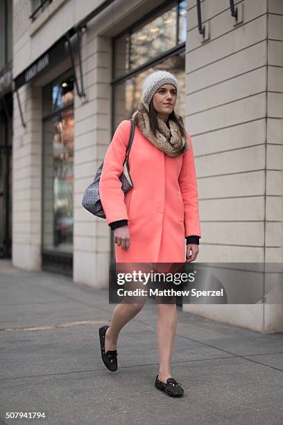 Katie McGraw is seen on Oak Street wearing grey cashmere/wool Club Monaco hat, Badgley Mischka faux fur scarf, bright salmon J.Crew wool coat, Goyard...