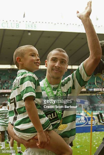 Celtic's Swedish striker Henrik Larsson does a lap of honour with his son after being presented with the Scottish Premier League Trophy after the...