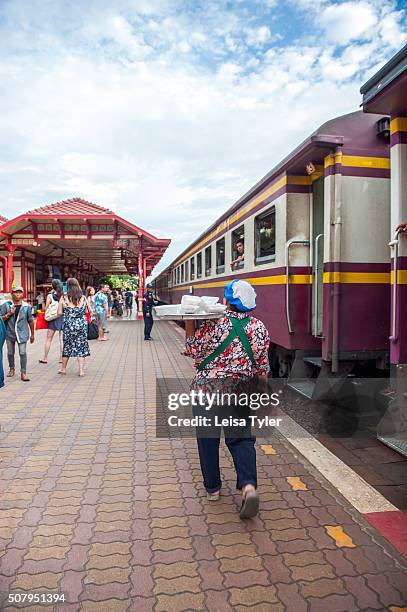 Woman hawking take away dishes to people on the train at the historical railway station in Hua Hin, Thailand.