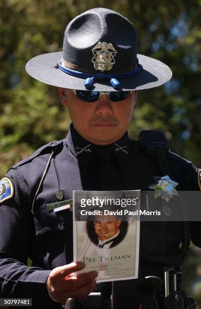 San Jose Police Officer Minh Phan reads a memorial card passed out at a service held by the family of Cpl. Pat Tillman for Tillman, who was killed in...