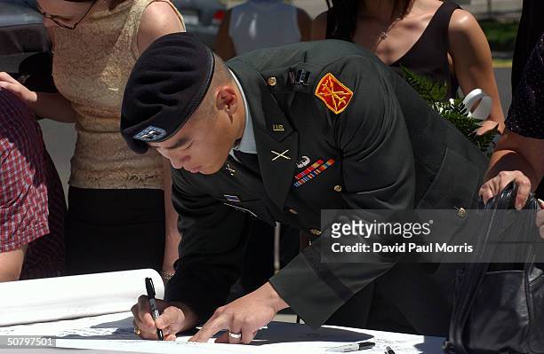 Captain Simon Kim signs a memorial banner during a service held by the family of Cpl. Pat Tillman for Tillman, who was killed in action in...