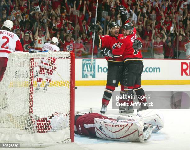 Curtis Joseph of the Detroit Red Wings lays dejected in his crease as Martin Gelinas of the Calgary Flames celebrates his overtime game-winning goal...