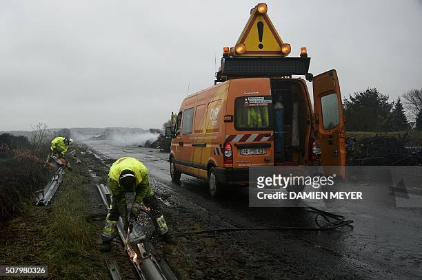 Employees clean the RN165 highway near Arzal, western France, on February 2, 2016 after a week of demonstrations and road blockades by farmers....