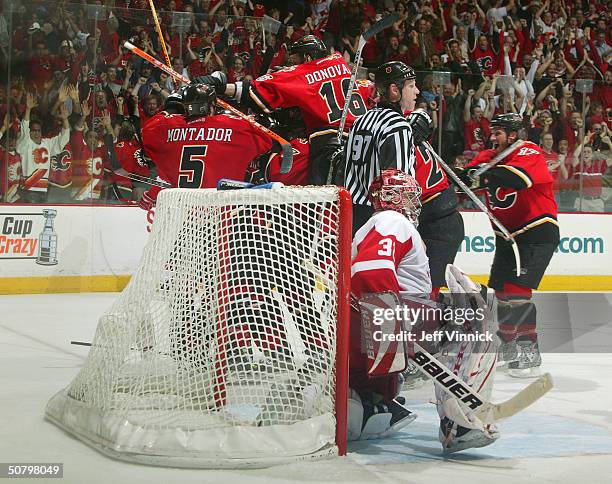 Curtis Joseph of the Detroit Red Wings sits dejected in his crease as Martin Gelinas of the Calgary Flames is mobbed by teammates after scoring the...