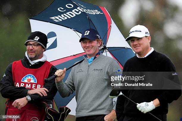 Brandt Snedeker prepares to tee off the 18th hole while looking on with caddie Scott Vail and on the 18th tee during the final round of the Farmers...