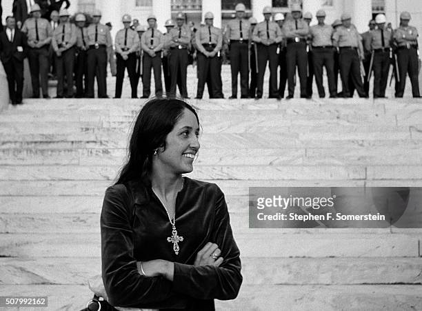 Folk singer and activist Joan Baez stands in front of state police on State House steps at the end of the Selma To Montgomery Civil Rights March on...