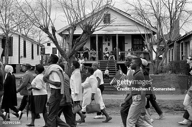 Marchers pass by a house with people on the porch on route 80, Jefferson Davis Highway during the Selma to Montgomery civil rights march on March 25,...