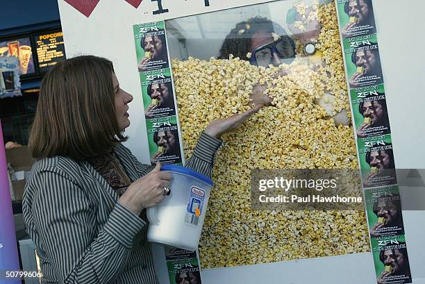 Correspondent Jeanne Moos offers salt to Crazy Legs Conti as he eats his way out of a box filled with popcorn to mark the premiere of the film "Crazy...