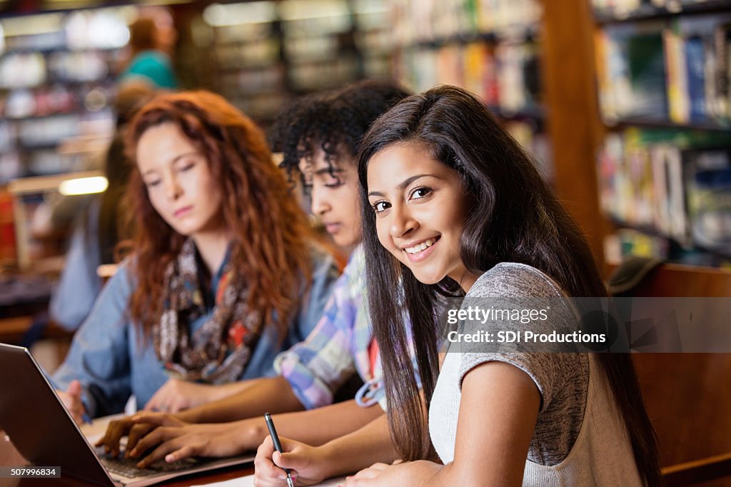 Indio adolescente estudiando en la biblioteca de la Universidad de edad con amigos