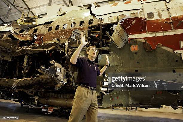 Jim Wildey of the National Transportation Safety Board gives the press a tour of the 93-foot section of the TWA Flight 800 fuselage that sits inside...