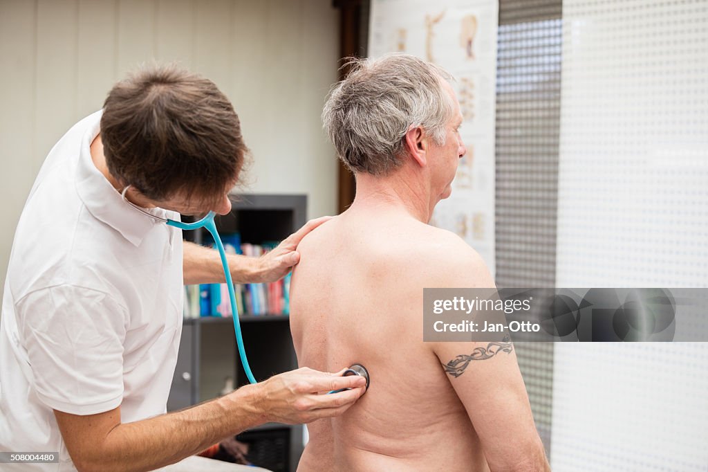 Doctor checking lung of mature patient