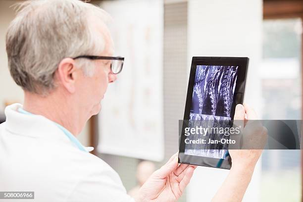 arzt überprüfen mri bilder auf tablet pc - orthopäde stock-fotos und bilder