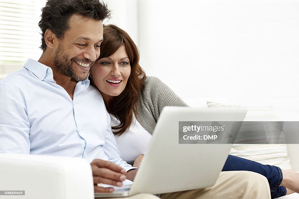 Happy interracial couple using laptop