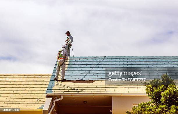 zwei männer malen ein dach eines hauses - roof tile stock-fotos und bilder