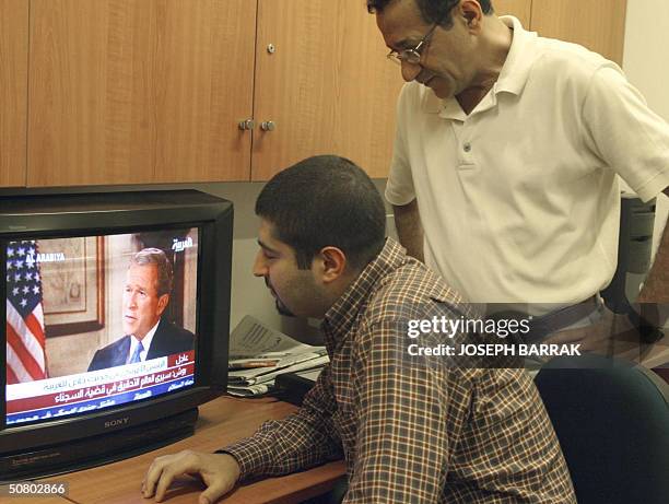 Two Lebanese men listen to US President George W. Bush's interview with the Dubai-based Arab news network Al-Arabiya 05 May 2004. Bush, who used Arab...