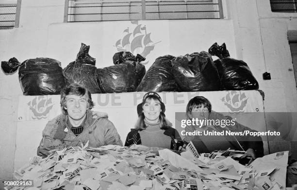 Television presenters Peter Purves, Lesley Judd and John Noakes pose together with piles of used postage stamps to launch the annual Blue Peter...