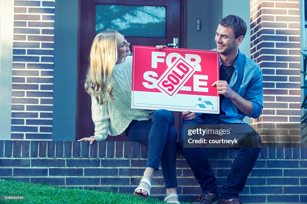 Couple sitting in front of a new home.