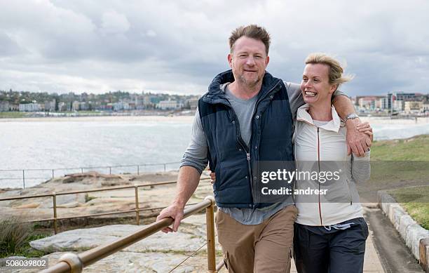 australisches paar zu fuß am strand - couple australian stock-fotos und bilder