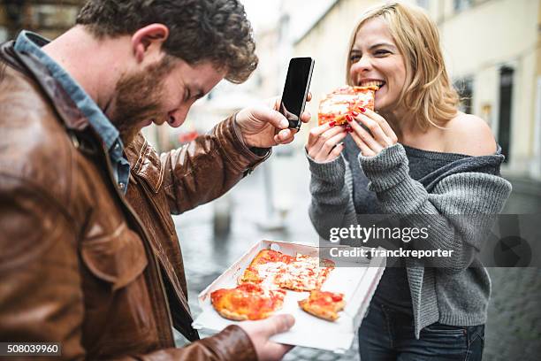 pareja comiendo una pizza hecha en italia y tomando fotografías - friends sharing mediterranean fotografías e imágenes de stock