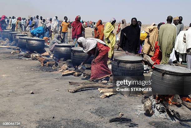 Women cook in pots heated up with firewood at an Internally Displaced Persons camp at Dikwa, in Borno State in north-eastern Nigeria, on February 2,...