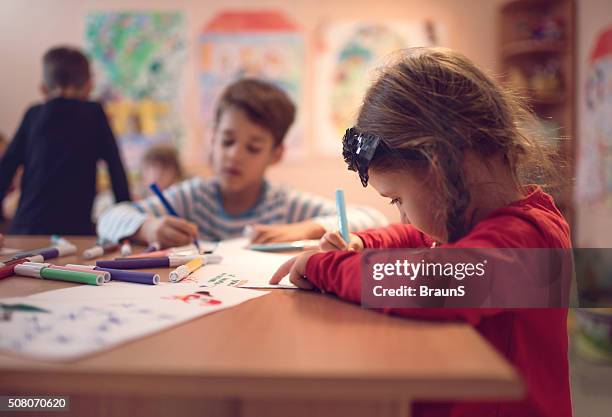 small girl drawing on a class in a preschool. - child's drawing stock pictures, royalty-free photos & images