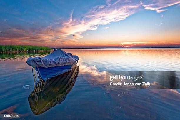 blue boat at sunset - harderwijk stockfoto's en -beelden