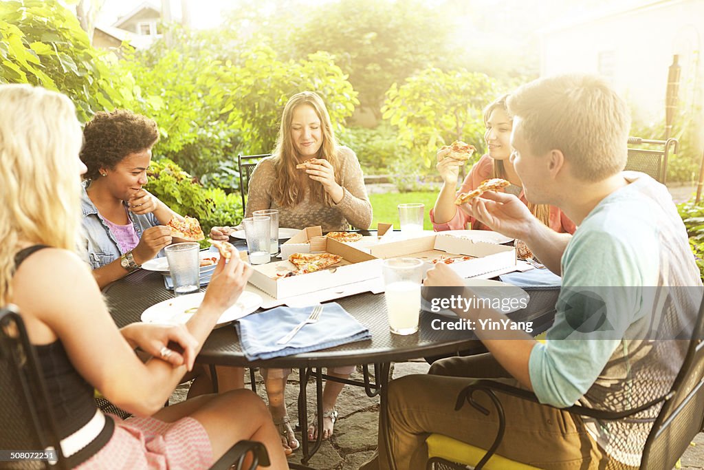 Teenage Friends Sharing Pizza Dinner at Summer Backyard Patio Table