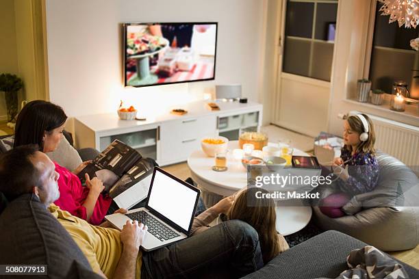 family using technologies in living room - familie fernsehen stock-fotos und bilder