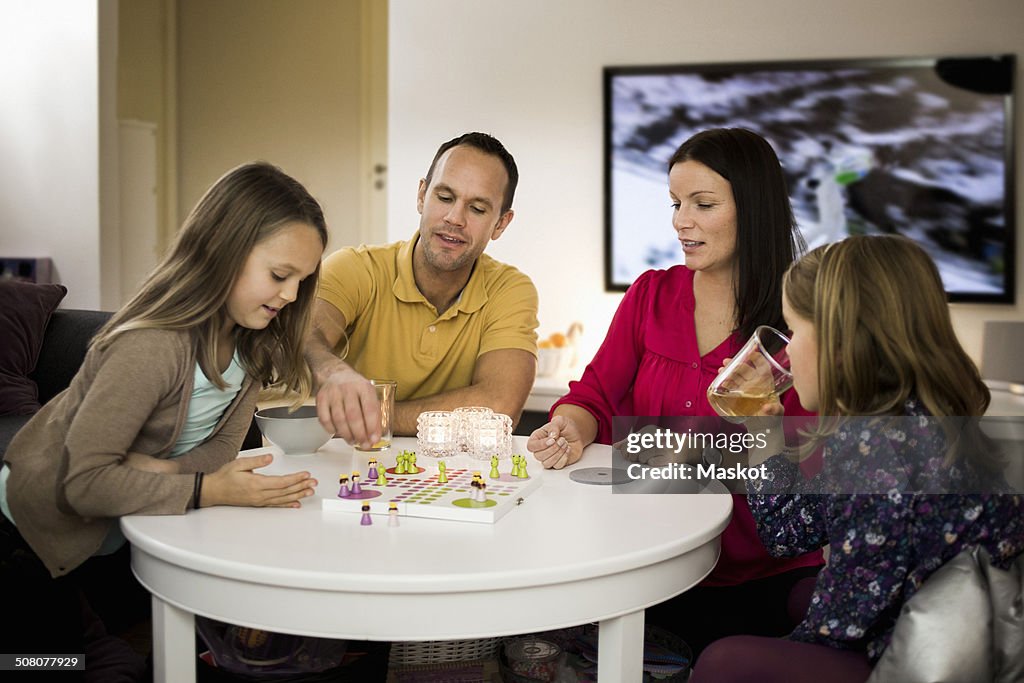 Family playing ludo in living room