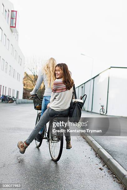 teenage girls riding bicycle on high school campus - friends cycling stock pictures, royalty-free photos & images