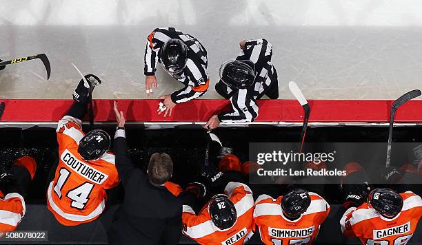 Head Coach of the Philadelphia Flyers Dave Hakstol speaks with Referee Kyle Rehman and Linesman Brandon Gawryletz during a stoppage in play against...