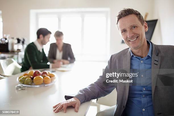 portrait of confident businessman at desk in office - fruit bowl stock pictures, royalty-free photos & images