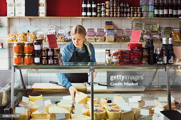 saleswoman working at display cabinet in supermarket - deli fotografías e imágenes de stock